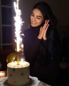 a woman holding her hand up to a birthday cake with sparklers on the top