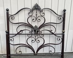 a metal bed frame with ornate designs on the headboard and foot board, against a white wall