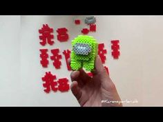 a hand holding a small green toy in front of some red and white pixeles