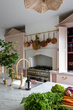 a kitchen with lots of vegetables on the counter and an oven in the back ground