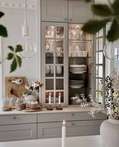 a white kitchen with candles and dishes on the counter