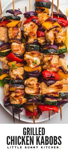 grilled chicken kabobs on a white plate with lemon wedges