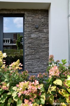 an open door to a house with flowers in the foreground