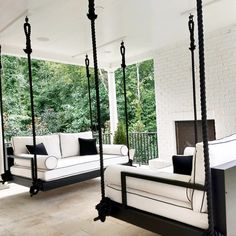 a porch with two white couches and a black iron swing bed in the middle