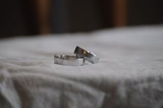 two wedding rings sitting on top of a bed