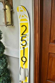 a yellow and white snowboard leaning up against a wooden door frame next to a christmas tree