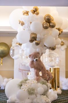 a teddy bear sitting on top of a bunch of balloons in the shape of clouds