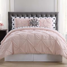 a bed with pink comforter and pillows in a room