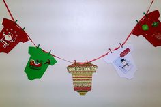 some red and green christmas decorations hanging from a line on a white wall in the corner