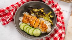 a bowl filled with rice, cucumber and chicken on top of a table