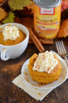 two pumpkin desserts with whipped cream on top are sitting on a plate next to a cup of coffee