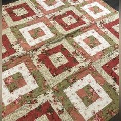 a red and green quilt on top of a wooden floor