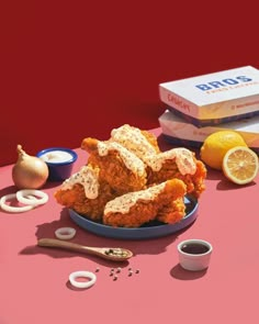 fried chicken on a blue plate with lemons, garlic and seasoning next to it