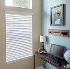 a laptop computer sitting on top of a wooden desk next to a window covered in blinds