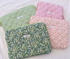 four flowered pouch bags sitting on top of a white sheet