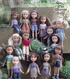 a group of dolls sitting on top of a stone wall