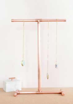 a pair of gold earrings hanging from a metal stand on top of a carpeted floor