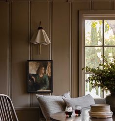 a table with two glasses of wine on it next to a potted plant in front of a window