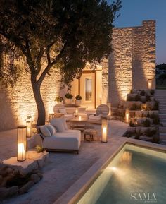 an outdoor living area lit up at night with candles and lights on the couches