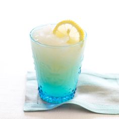 a blue and yellow drink sitting on top of a table next to a white towel