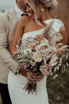 a bride and groom standing together with their bouquet