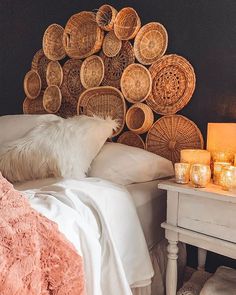 a white bed topped with lots of pillows next to a night stand filled with candles