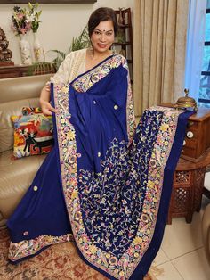 Update! - Zynah covered by LBB - https://lbb.in/bangalore/zynah-designs-handloom-sarees/ Elevate your style quotient with our Navy Blue Pure Crepe Silk Hand Embroidered Parsi Gara Saree, a stunning piece of authentic vintage art that is sure to make you stand out. Adorned with intricate nature-inspired motifs and multi-color thread embroidery, this saree boasts of a beautiful combination of small colorful floral butis in the body. The saree features a double layer of embroidery to create a uniqu Blue Bohemian Blouse Piece With Zari Work, Bohemian Blue Raw Silk Traditional Wear, Blue Silk Saree With Floral Embroidery, Blue Pallu Embroidered Raw Silk Fabric, Blue Raw Silk Embroidered Fabric With Pallu, Blue Embroidered Pallu Raw Silk Fabric, Designer Blue Embroidered Saree, Blue Bohemian Raw Silk Saree, Blue Saree With Floral Embroidery In Traditional Drape