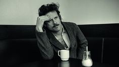 a black and white photo of a man sitting at a table with a coffee mug