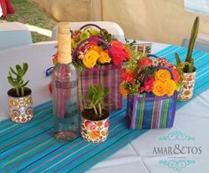 colorful flowers and plants in vases sitting on a table with a blue striped tablecloth