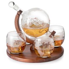 four glasses and a decanter with a ship in it on a wooden tray