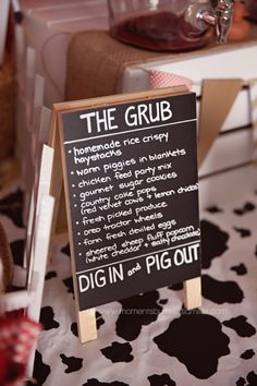 a sign that says the grub is on top of a cow print table cloth