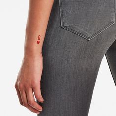 a woman with a small red heart tattoo on her left arm