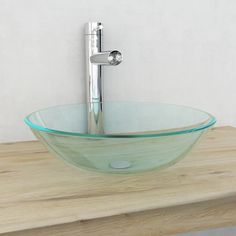 a glass bowl sink sitting on top of a wooden counter next to a faucet