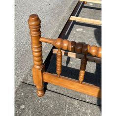 a bed frame with wooden posts and spindles on the bottom, sitting on concrete