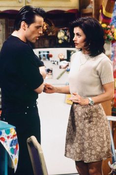 the young man and woman are standing in front of a refrigerator door talking to each other