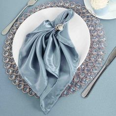 a white plate topped with a blue napkin next to silverware and utensils