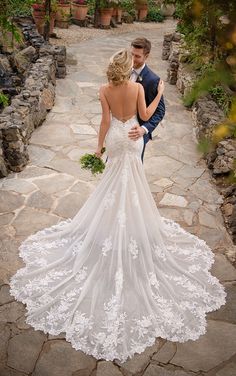 a bride and groom standing in the middle of a stone path looking at each other