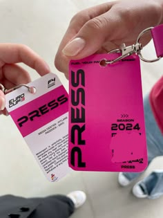 a person holding up a pink business card with a keychain attached to it