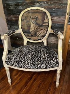 a leopard print chair sitting on top of a hard wood floor next to a wooden wall