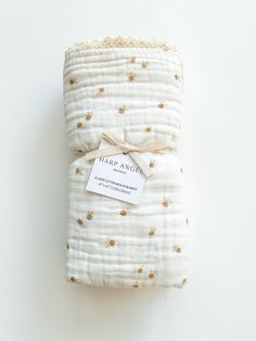 a white blanket with gold polka dots on it and a tag that says tararangg