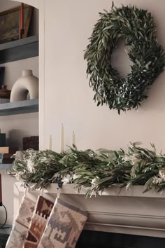 a wreath is hanging on the mantle in front of a fireplace