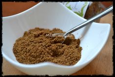 a white bowl filled with spices on top of a wooden table