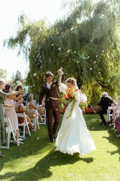 a bride and groom walking down the aisle after their wedding ceremony with bubbles in the air