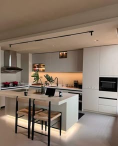 a modern kitchen with an island in the middle and two stools at the end