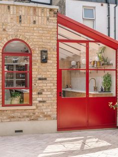 a brick building with red glass doors on the outside and windows in the inside, along with potted plants