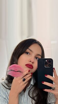 a woman taking a selfie in front of her cell phone with lipstick on it