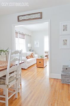 a living room with hard wood floors and white furniture