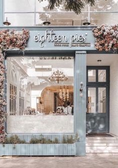 a store front with flowers growing on the outside and in the windows, there is a blue door that says eight fifteen pies