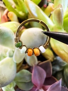 a close up of a ring with beads on it and some flowers in the background