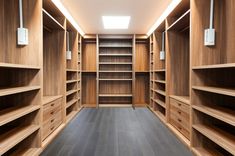 an empty walk - in closet with wooden shelves and drawers